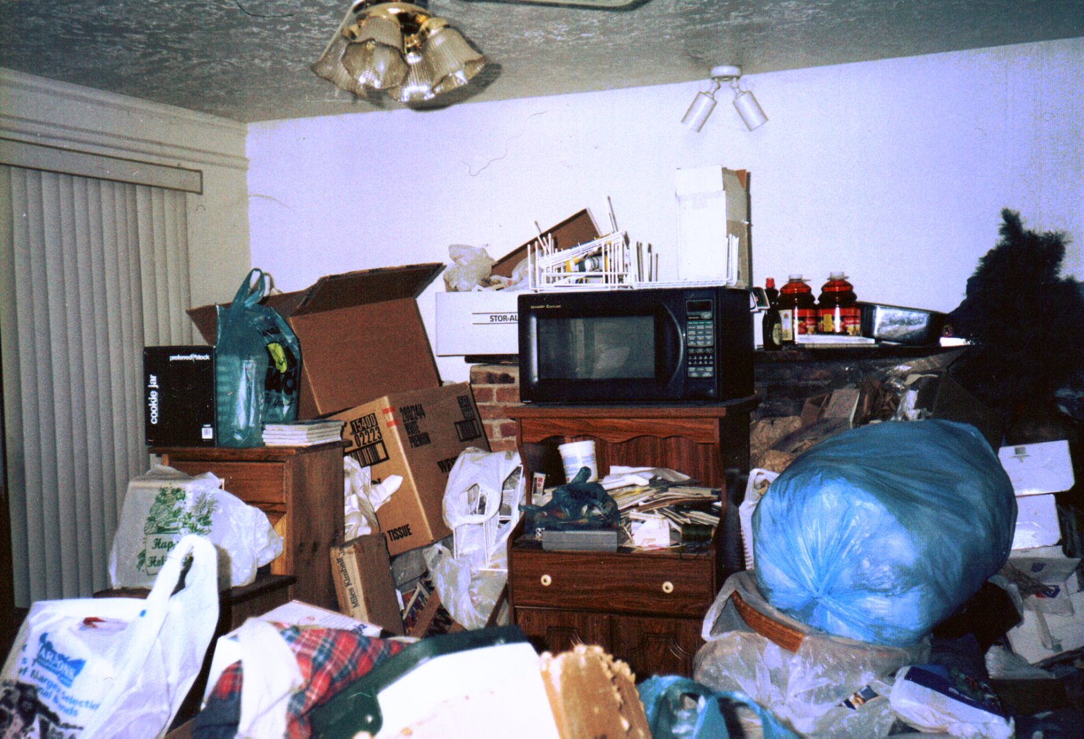 A room piled high with junk, cardboard boxes and garbage bags