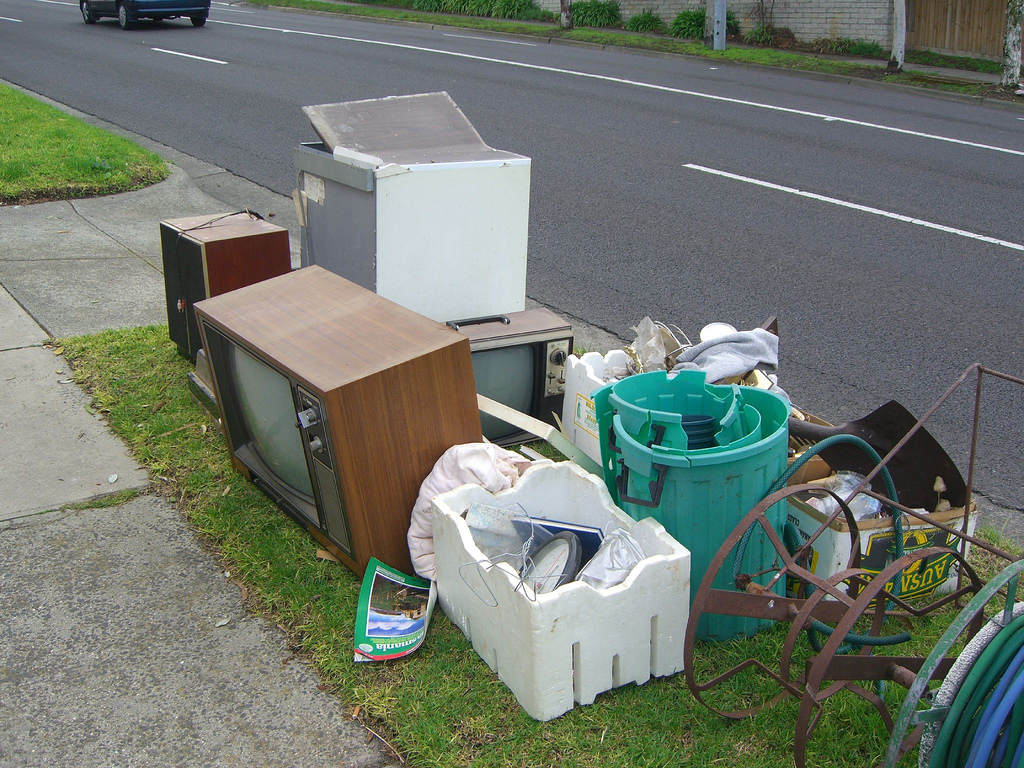 Some junk by the curb including several old televisions, a wire hose spool
