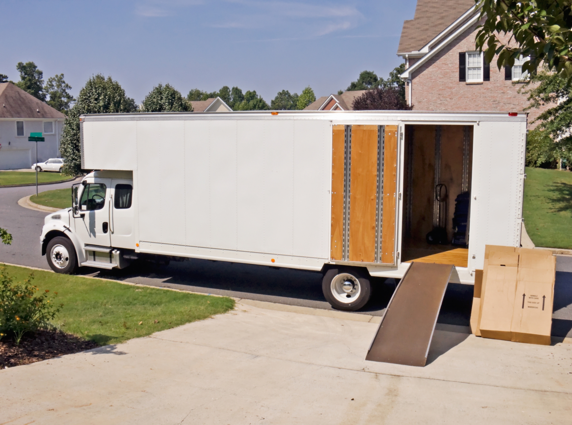 A white moving truck with a ramp set up in to the back